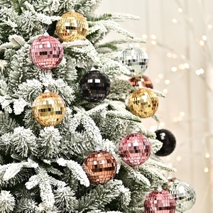 Colorful mirrored disco ball Christmas ornaments hanging on a snowy holiday tree