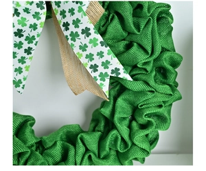 Close-up of green burlap St. Patrick's Day wreath with clover ribbons and rustic texture