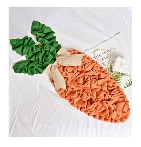 Detail of burlap carrot Easter ornament with beige bow tie on a white fabric background