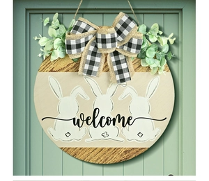 Detail of wooden welcome door sign with white bunnies, buffalo plaid bow and greenery