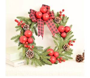 Close-up of Christmas wreath with red berries, pine cones and red-black buffalo plaid bow