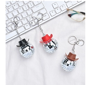Close-up of three disco ball keychains with miniature denim hats in black, red and brown