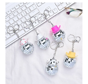 Close-up of disco ball keychains with mini cowboy hats in pink, white, and cow print patterns