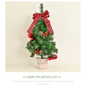 Close-up of artificial pine Christmas tree with red berries and plaid bow in a metal bucket
