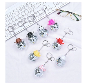 Detail of colorful disco ball cowboy hat keychains reflecting on a textured background
