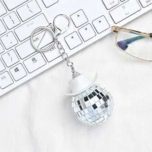 Disco ball keychain with white cowboy hat and silver mirror finish on a texture background