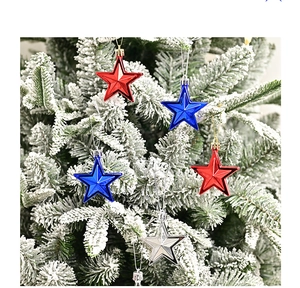 Close-up of red, blue and silver star ornaments hanging on a snowy Christmas tree branch