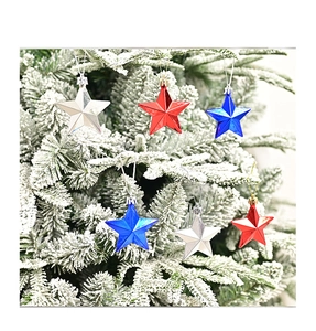 Red silver and blue star ornaments hanging on a snowy Christmas tree branch