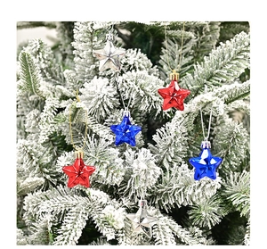 Close-up of red, blue and silver star ornaments hanging on a snowy Christmas tree