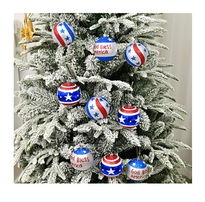 Close-up of red white and blue God Bless America Christmas ornaments on snowy tree branches