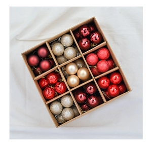 Flat lay of red and gold Christmas ornaments in a kraft paper box with nine grid dividers