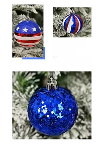 Detail of red white and blue American flag style Christmas ornaments on snowy pine branches