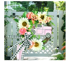 Détail d'une couronne de tournesols avec camion rose et ruban sur une porte blanche