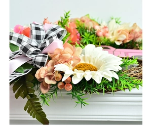 Détail d'une couronne de fleurs roses et marguerites avec un nœud en ruban à carreaux