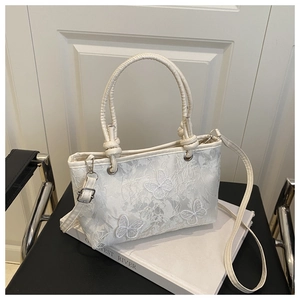 Détail du sac en dentelle blanche avec broderie papillon 3D et doubles poignées fixes