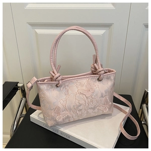 Détail d'un sac à main en dentelle rose avec broderie papillon sur un livre de déco