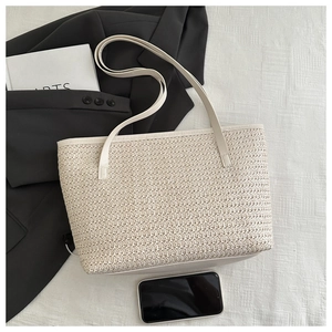 Detailed top view of a cream woven straw tote bag with thin leather shoulder straps