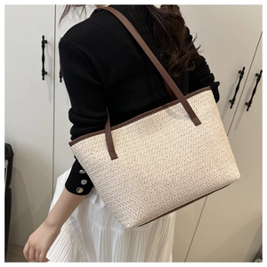 Detailed side view of large woven tote bag with brown leather straps worn by a model
