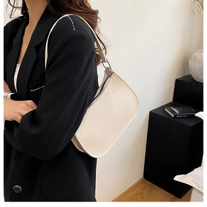 Close-up of a cream hobo bag with litchi grain texture worn by a model in a studio