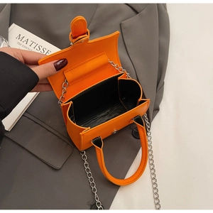 Close-up of vibrant orange mini handbag with silver chain and magnetic clasp interior