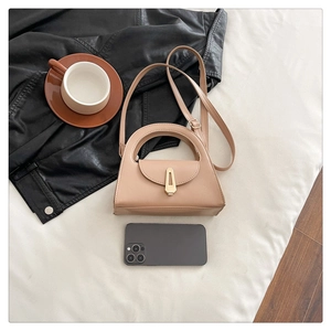 Mini beige trapezoid handbag with gold buckle shown next to smartphone for size scale