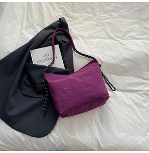 Close-up of purple nylon tote bag with black and white woven strap and drawstring detail