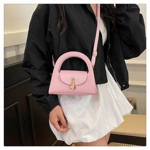 Model wearing a light pink minimalist crossbody bag with golden buckle and sleek handle