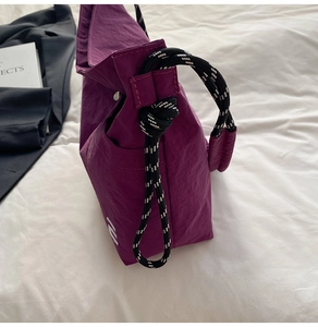 Detail of purple nylon tote bag with black and white braided rope handle and knot detail