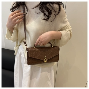Close-up of brown woven texture handbag with gold infinity twist lock on model