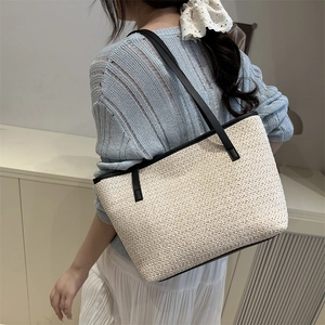 Large woven tote bag for summer beach use with black straps and minimalist straw design