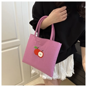 Detail of purple nylon tote bag featuring apple embroidery and lightweight shoulder strap