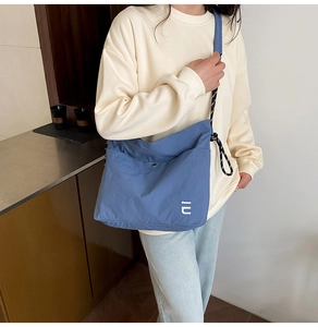 Detail of blue nylon crossbody bag featuring lightweight crinkled fabric and white logo