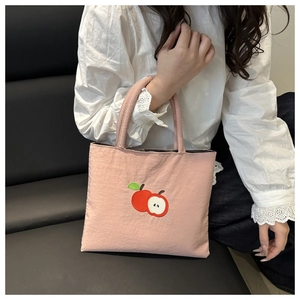 Close-up of pink nylon handbag featuring detailed red apple embroidery and fabric handle