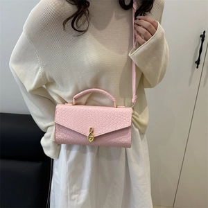 Pink woven texture crossbody bag with infinity gold buckle shown with a beige outfit