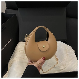 Details der camelfarbenen Crescent-Tasche mit Goldkette und Knopf auf Seidenhintergrund