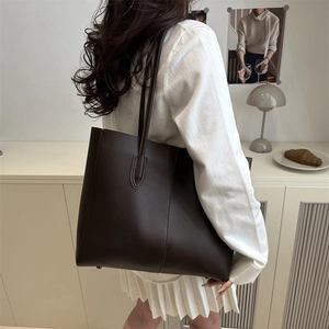 Minimalist large coffee brown tote bag in textured leather worn over the shoulder