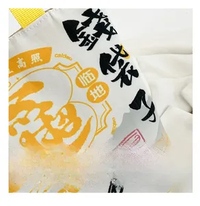 Detail of white canvas bag with black calligraphy, yellow patterns and woven handles