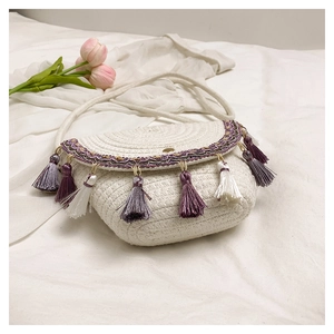 Detailed view of cream woven shoulder bag with bohemian tassels and colorful embroidery