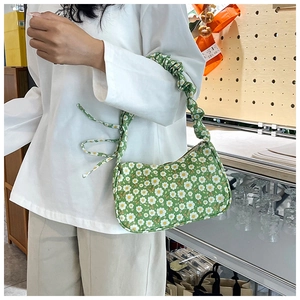 Close-up of green floral shoulder bag with daisy pattern and ruched cloud strap detail
