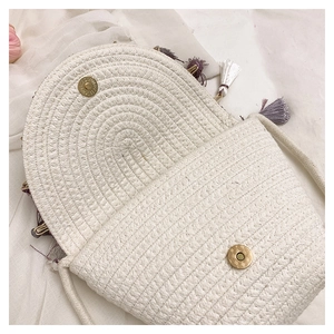 Detail of cream straw envelope bag with purple tassels and magnetic buckle closure