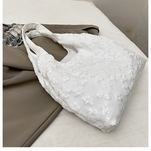 Detail of white tote bag featuring soft 3D floral bubble texture and wide shoulder strap