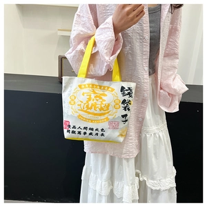 Detail of canvas tote bag featuring vintage Chinese graphics and yellow woven handles