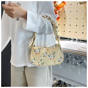 Close-up of yellow daisy floral print crescent bag with ruffled cloud handle and canvas texture