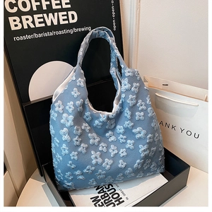 Detail of light blue tote bag featuring 3D floral textures and delicate embroidery