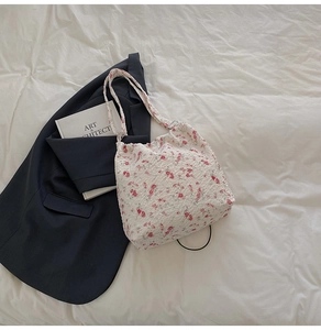 Detail of floral seersucker shoulder bag with pink blossom patterns on white fabric