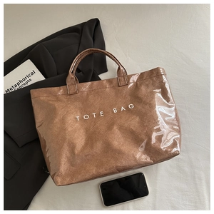 Detail of a brown wrinkled tote bag with white TOTE BAG text print on a fabric surface