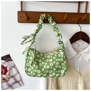 Detail of green floral hobo bag featuring scrunchie strap and bow on a wooden hook
