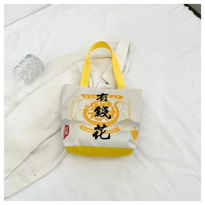 Detail view of canvas tote bag with 'Rich' print and vibrant yellow color accents