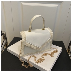 Dettaglio della mini borsa bianca con frange delicate e tracolla a catena d'oro