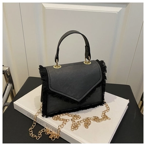Dettaglio borsa nera in tessuto con eleganti frange e tracolla con catena in metallo dorato
